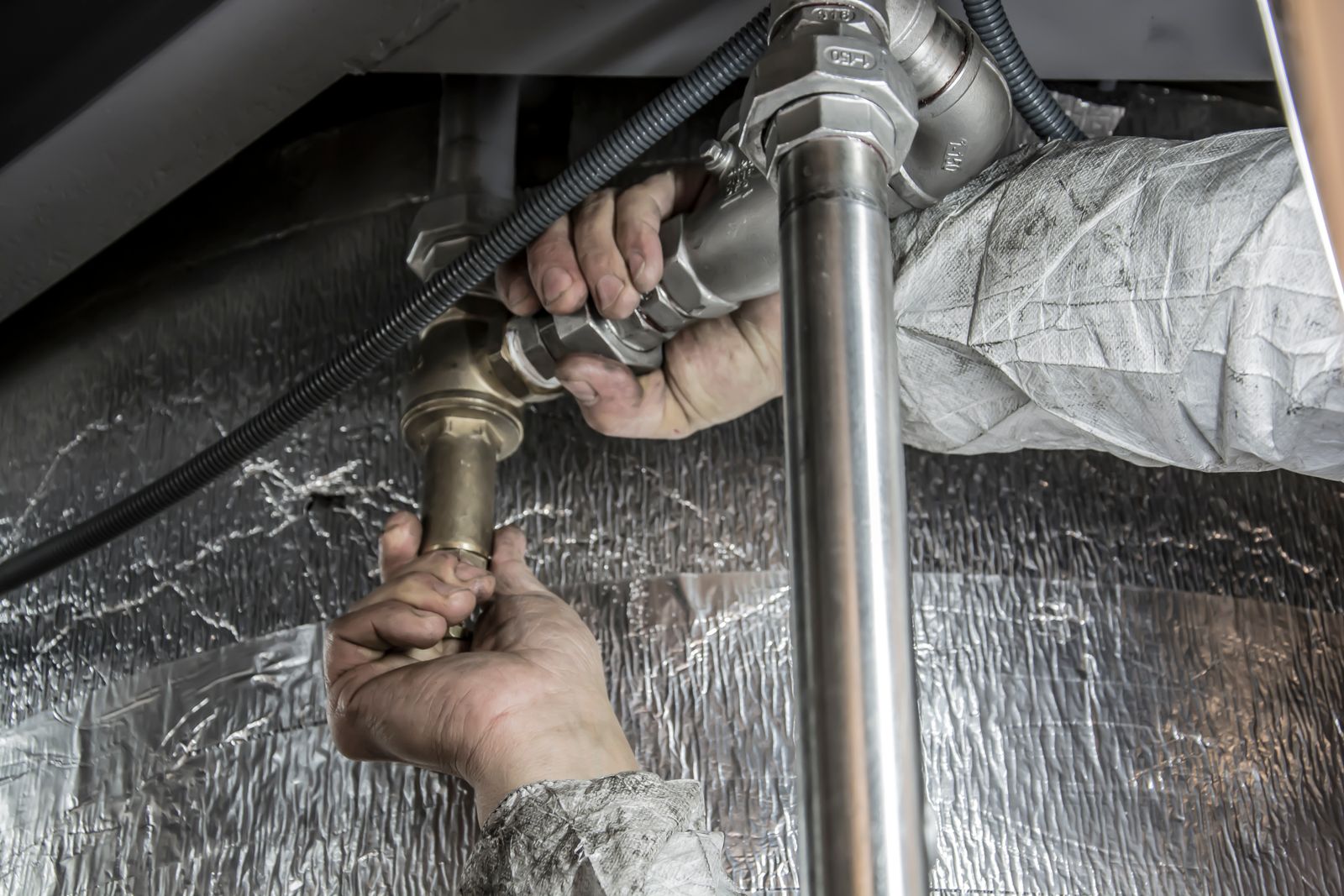 Sample image of hands fitting steel pipework under insulation